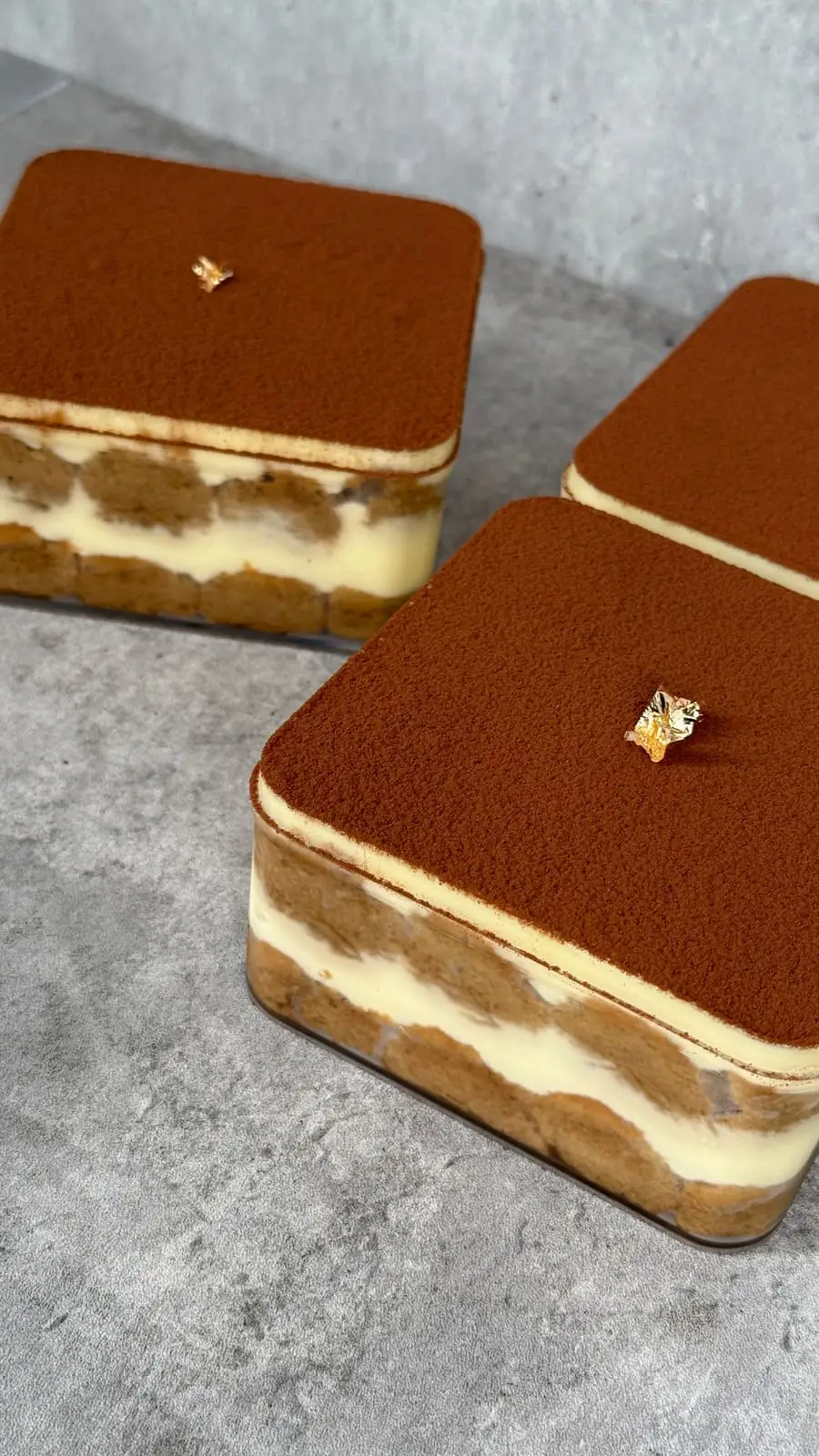 Individual tiramisu desserts layered with mascarpone cream, coffee-soaked sponge, and cocoa powder.